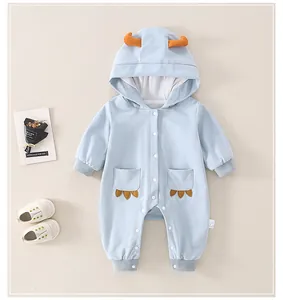 Detail of light blue cotton baby romper with hood and orange 3D accents and soft shoes