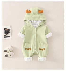 Detail of baby dinosaur hooded jumpsuit with orange horn accents and claw embroidery
