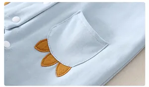 Detail of light blue cotton baby romper with white snaps and yellow felt decorations