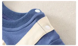 Detailansicht der Baby-Strampler-Schulter mit weißen Druckknöpfen und blauem Baumwollstoff