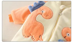 Close-up of heart-shaped metal zipper and orange dinosaur embroidery on baby romper