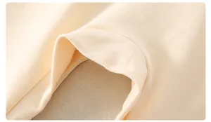 Detail aus weichem cremefarbenem Baumwollstrick mit glatten Doppelnähten am Baby-Body