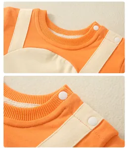 Detail of the orange baby romper with white shoulder straps and snaps for easy dressing