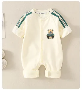 Detail of baby cotton romper featuring cartoon bear patch and green shoulder stripes