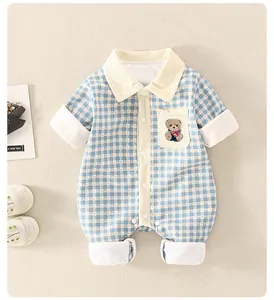Détail d'une grenouillère matelassée pour bébé avec motif bleu à carreaux et petit ours