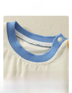 Détail de l'encolure côtelée bleue et bouton pression sur body bébé en coton à motifs