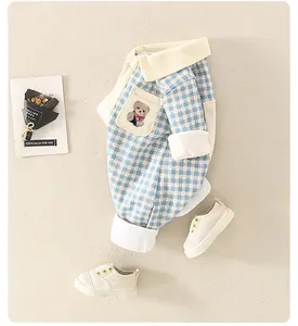Détail d'une grenouillère bébé à carreaux bleu clair avec broderie d'ours et col blanc doux