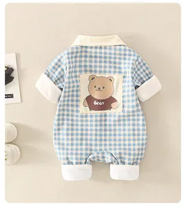 Détail d'une grenouillère bébé à carreaux bleus avec un écusson ours au dos