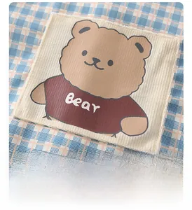 Détail d'appliqué ours et tissu vichy bleu sur barboteuse matelassée bébé