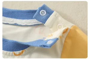 Détail de l'encolure du barboteuse en coton avec boutons pression et manches raglan