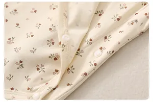Detalle macro del body para bebé en algodón acanalado con estampado floral y clips