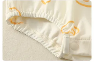 Détail du body bébé en coton avec tissu côtelé imprimé orange et bouton pression résine
