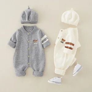 Detail of baby knitted romper set with bear embroidery and matching beret in neutral tones