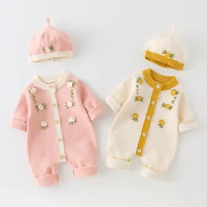 Detail of baby knitted rompers with delicate 3D flower embroidery and matching beanies