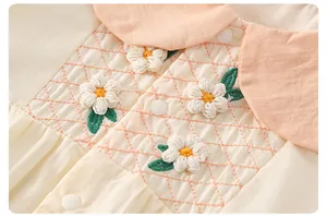 Detail von Baby-Baumwoll-Strampler mit Blumenstickerei und orangefarbenem Kragen