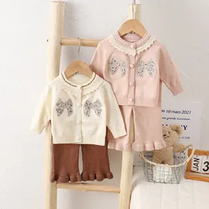 Detail of baby girl knitted cardigan and ruffled pants set with floral bow applique