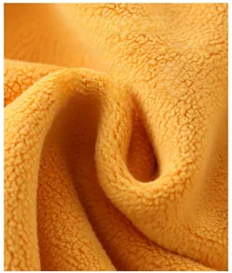 Close-up of thick orange double-sided fleece fabric showing soft and breathable texture
