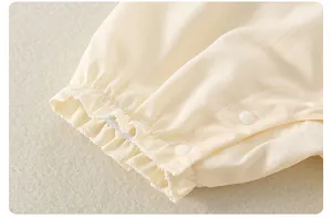 Detail eines Baby-Baumwoll-Stramplers mit Rüschenbündchen, Twill-Textur und Druckknöpfen