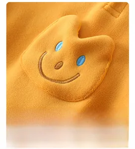 Detail of yellow fleece fabric with a cute embroidered smiley face on baby romper