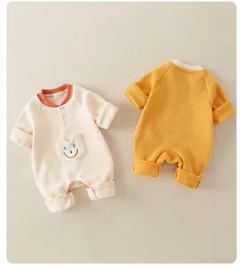 Detail of soft fleece baby rompers in beige and ginger yellow with smiley face patch