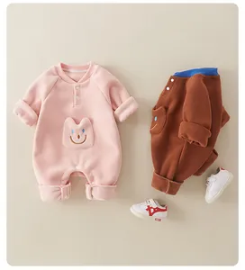 Flat lay of pink and brown fleece baby rompers with cute pocket and infant sneakers