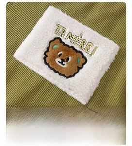 Detail of dark green corduroy baby romper featuring a cute bear embroidery patch