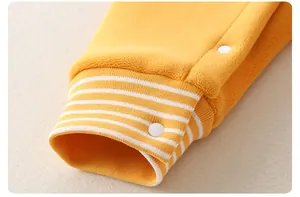 Detailed macro view of bright yellow fleece baby romper with striped ribbed cuffs and snap button