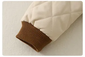 Detail of diamond quilted beige baby romper sleeve with brown ribbed elastic cuffs