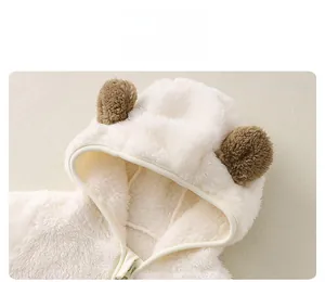 Close-up of white plush baby romper with cute brown 3D ears on hood and zipper detail