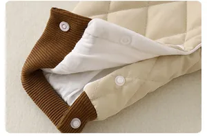 Detail of quilted baby romper featuring ribbed cuffs and white resin snap buttons