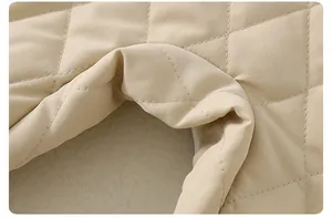 Detail of baby quilted romper showing diamond stitch texture and curved hem in beige