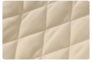 Macro view of beige quilted fabric with diamond stitching for baby romper