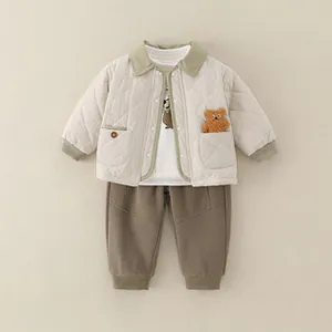 Flat lay of baby quilted jacket with bear detail, printed T-shirt and green joggers