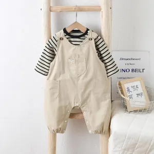 Detail of infant striped long sleeve shirt and khaki overalls on wooden ladder