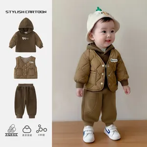 Detail of infant 3-piece set featuring quilted vest and fleece hoodie in brown tones