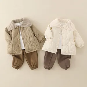 Flat lay of quilted winter baby jackets and pants set with knit collars in earthy tones