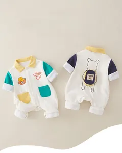 Detail of baby cotton romper featuring cartoon bear embroidery and contrast pockets