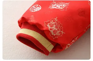 Dettaglio del polsino della tutina festiva rossa per neonati con ricami di leone d'oro