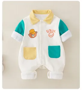 Detail of baby cotton romper featuring bear embroidery, smile text and colorful pockets