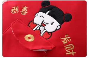 Close-up of red winter baby romper with festive embroidery and golden calligraphy