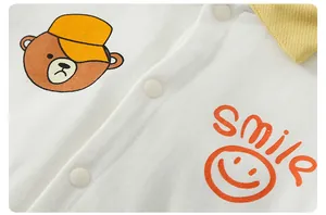 Detail of baby cotton romper featuring smile print and cute cartoon bear embroidery