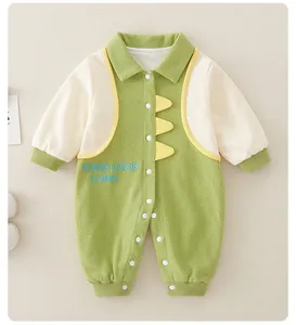 Detail of baby cotton dinosaur romper showing green fabric texture and button closure