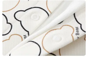 Macro detail of baby romper fabric with bear print and white resin snap buttons