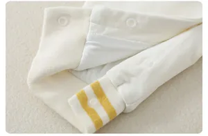 Detail of baby cotton romper showing yellow striped cuffs and white plastic snap buttons