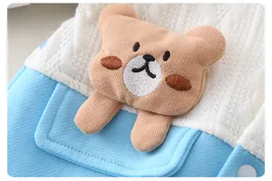 Detail of soft blue baby romper featuring a 3D stuffed teddy bear on a small pocket