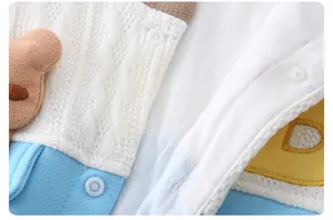 Detail of infant romper showing cotton fabric texture, bear patch, and snap buttons