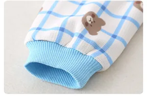 Detail of baby romper featuring blue waffle fabric, ribbed cuffs and cute bear print