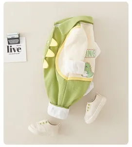 Detailed close-up of green waffle knit baby romper featuring 3D dinosaur fins and print