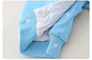 Detail view of cotton baby romper showing light blue fabric and white snap button closure