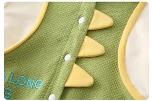 Close-up of baby romper with green waffle texture fabric and yellow dinosaur fin detail